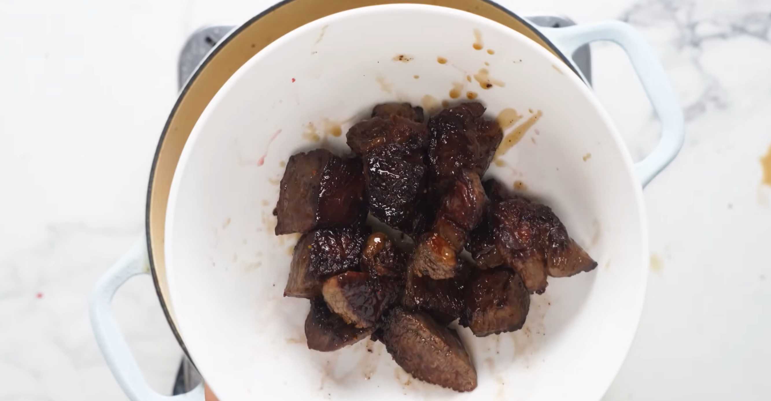 Налейте в кастрюлю растительное масло и обжарьте мясо порциями с обеих сторон и выложите в миску. Семейный мясной пирог-Шаг 2