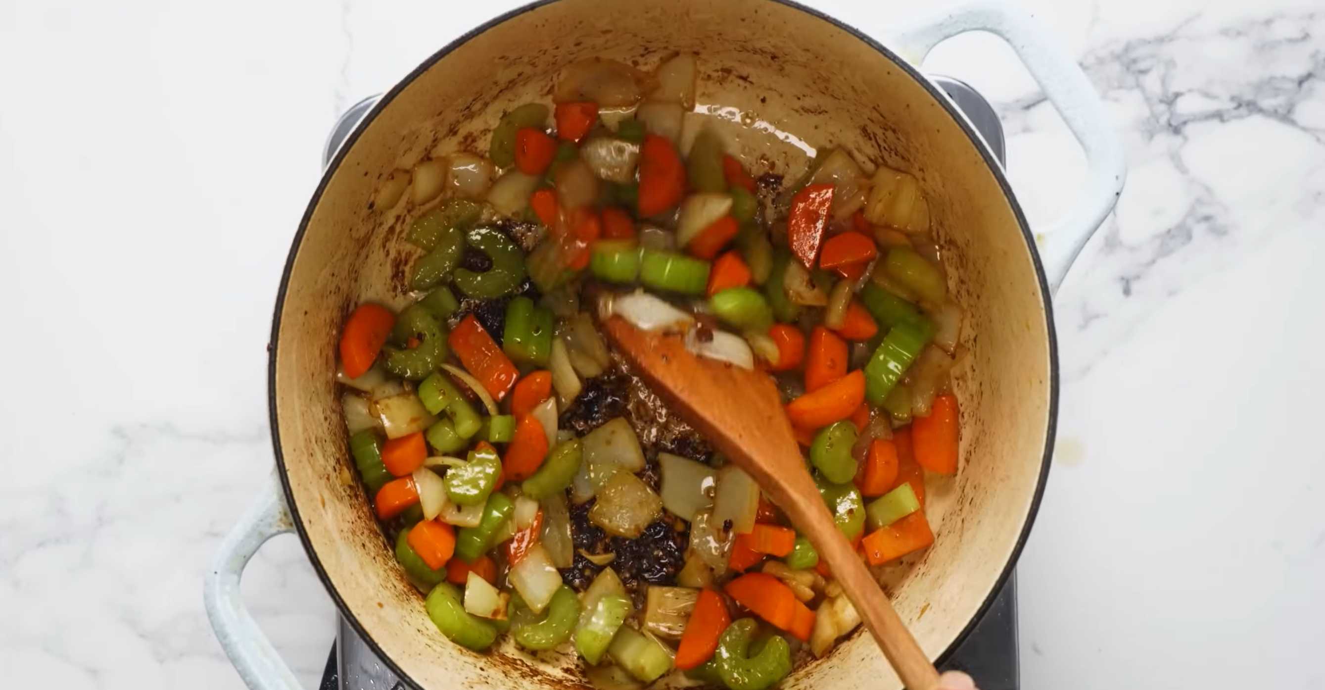 Нарежьте кусочками лук, сельдерей, морковь, раздавите чеснок, выложите в кастрюлю и слегка обжарьте. Семейный мясной пирог-Шаг 5