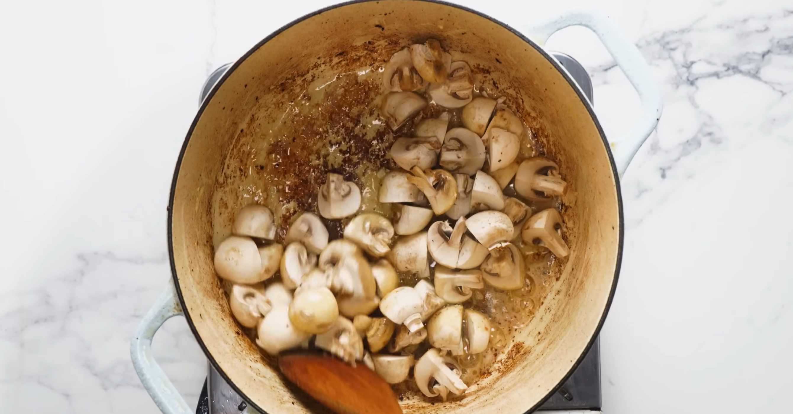 Растопите в той же кастрюле сливочное масло и обжарьте нарезанные кусочками небольшие шампиньоны. Семейный мясной пирог-Шаг 4