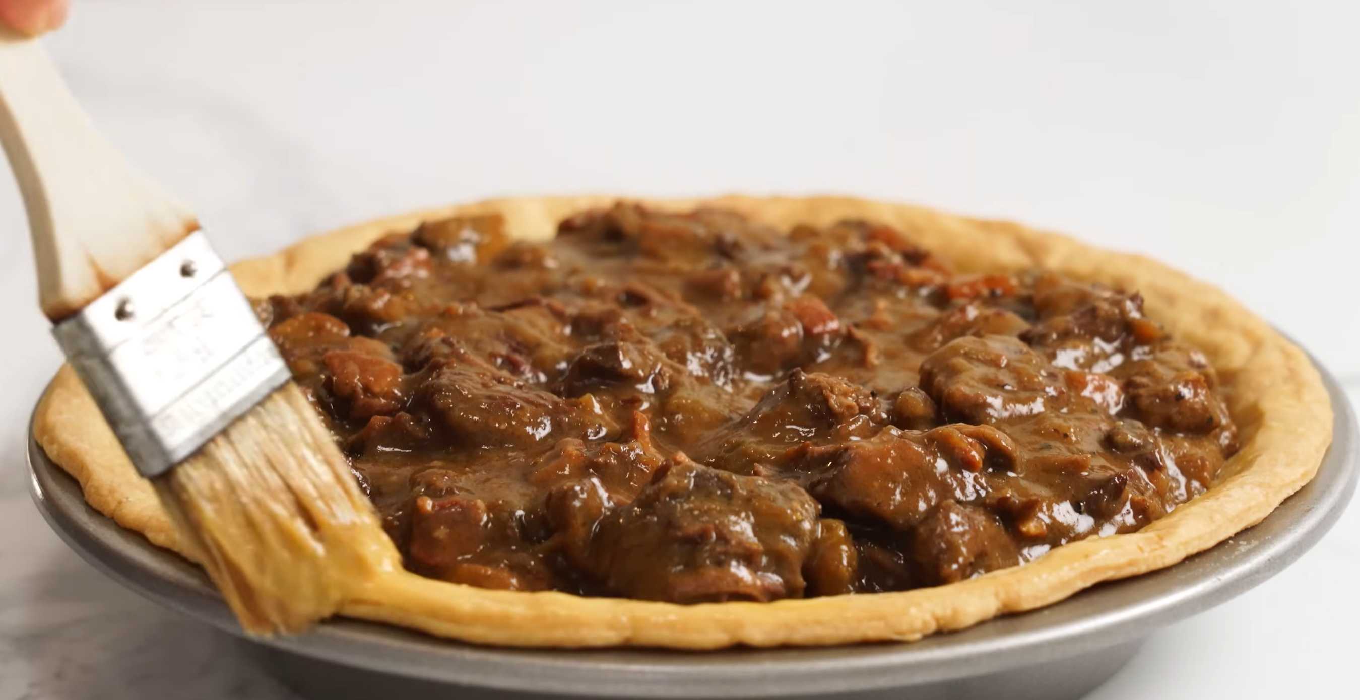 Выложите начинку в пирог в форме с небольшой горкой, смажьте края теста яйцом. Семейный мясной пирог-Шаг 16