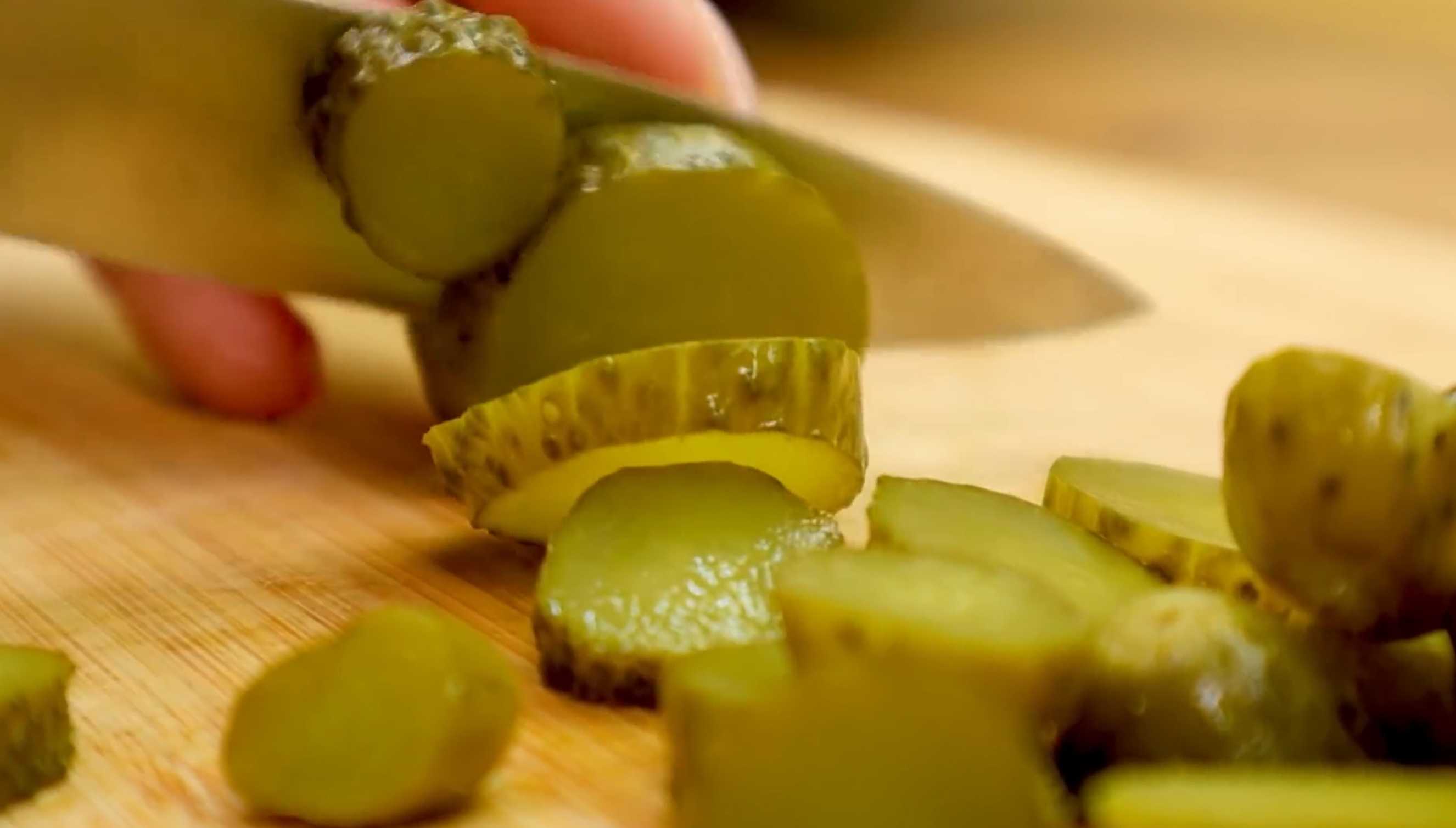 Пока морковь варится - нарезать сыр небольшими кубиками, зеленый лук - мелко, маринованные огурцы - колечками. Сложить нарезанное в миску. Немецкий рождественский салат-Шаг 2