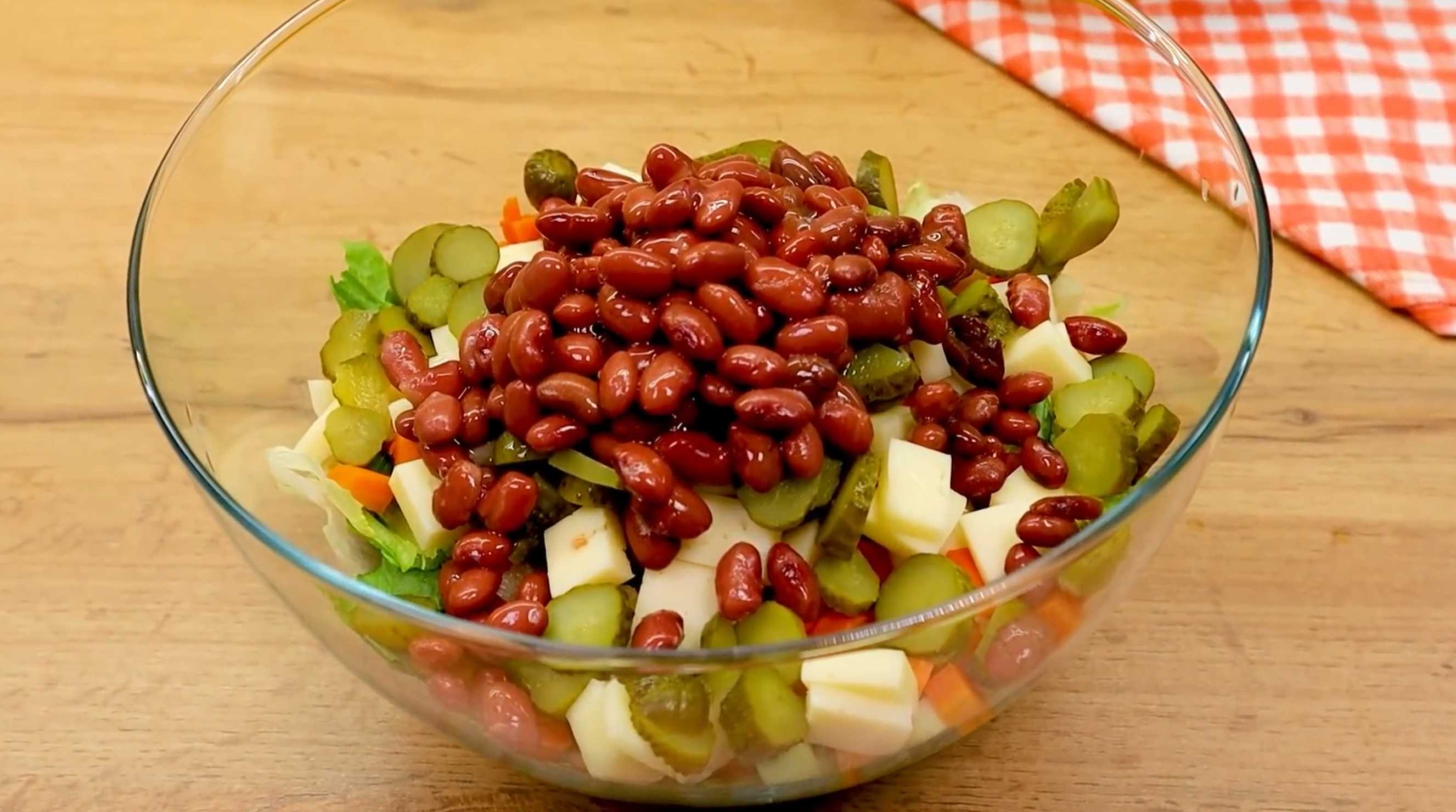 Охладить сваренную морковь и нарезать ее мелкими кубиками в миску с ранее нарезанными ингредиентами. Туда же руками разорвать на небольшие части листья зеленого салата. Добавить в салат фасоль. Немецкий рождественский салат-Шаг 4