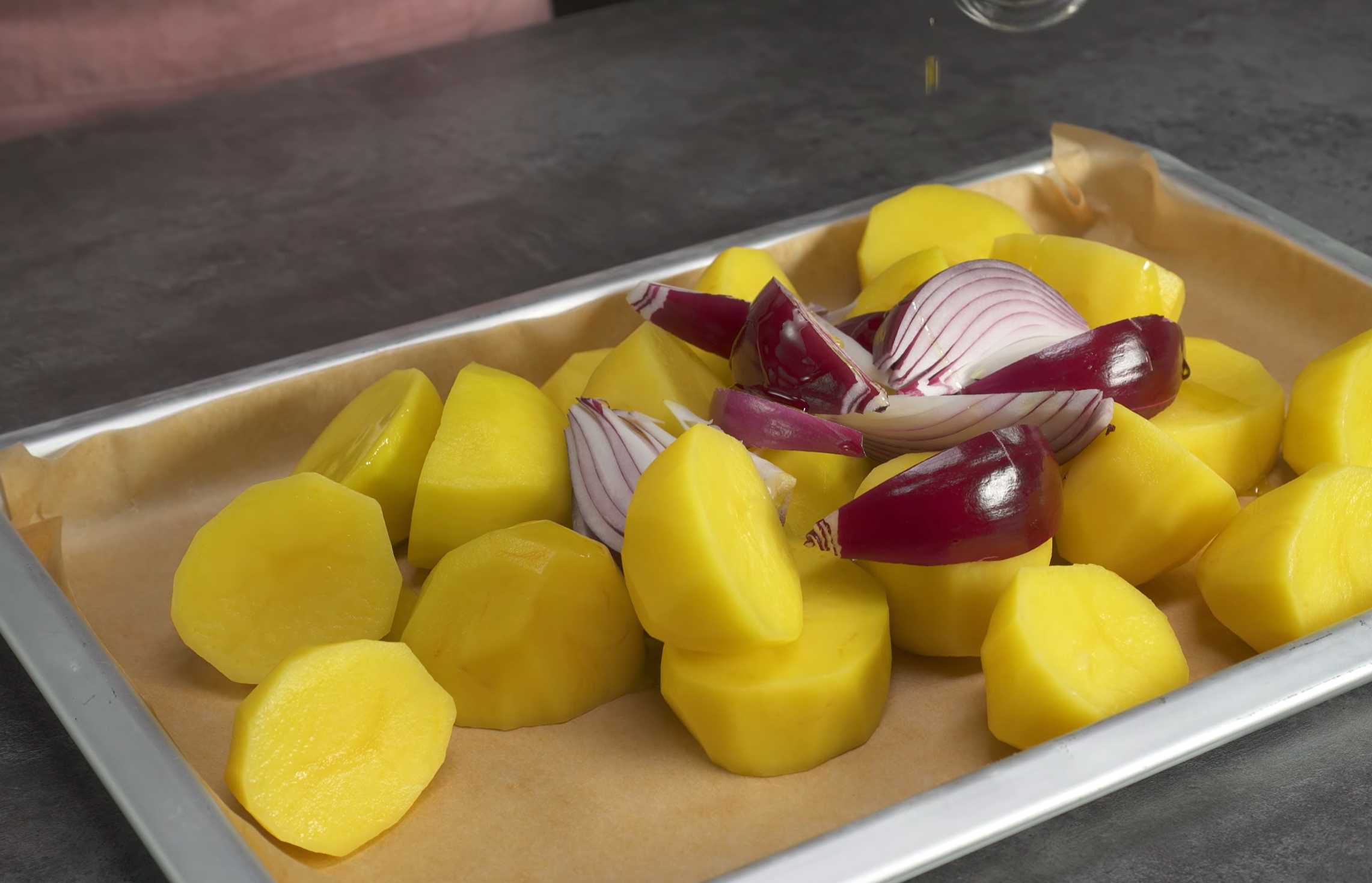 Крупно нарежьте красный лук и выложите на противень к картофелю. Полейте картофель и лук растительным маслом. Курица с прованскими травами и картошкой-Шаг 2