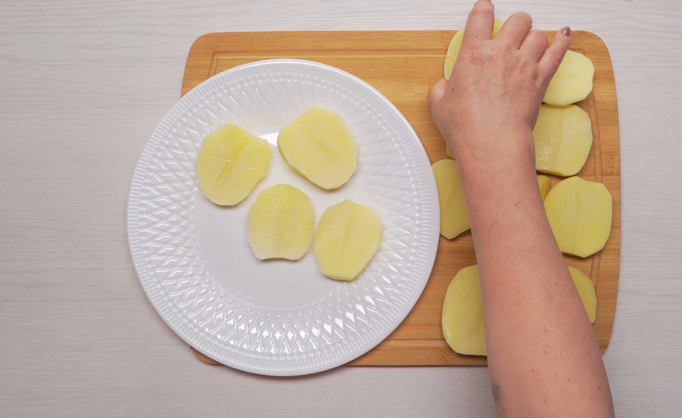 Очистите картофель от кожуры. Нарежьте картофель на кружки (или половинки, не толстые), выложите на тарелку и накройте крышкой для микроволновки. Золотистая жареная картошка на сковороде-Шаг 1