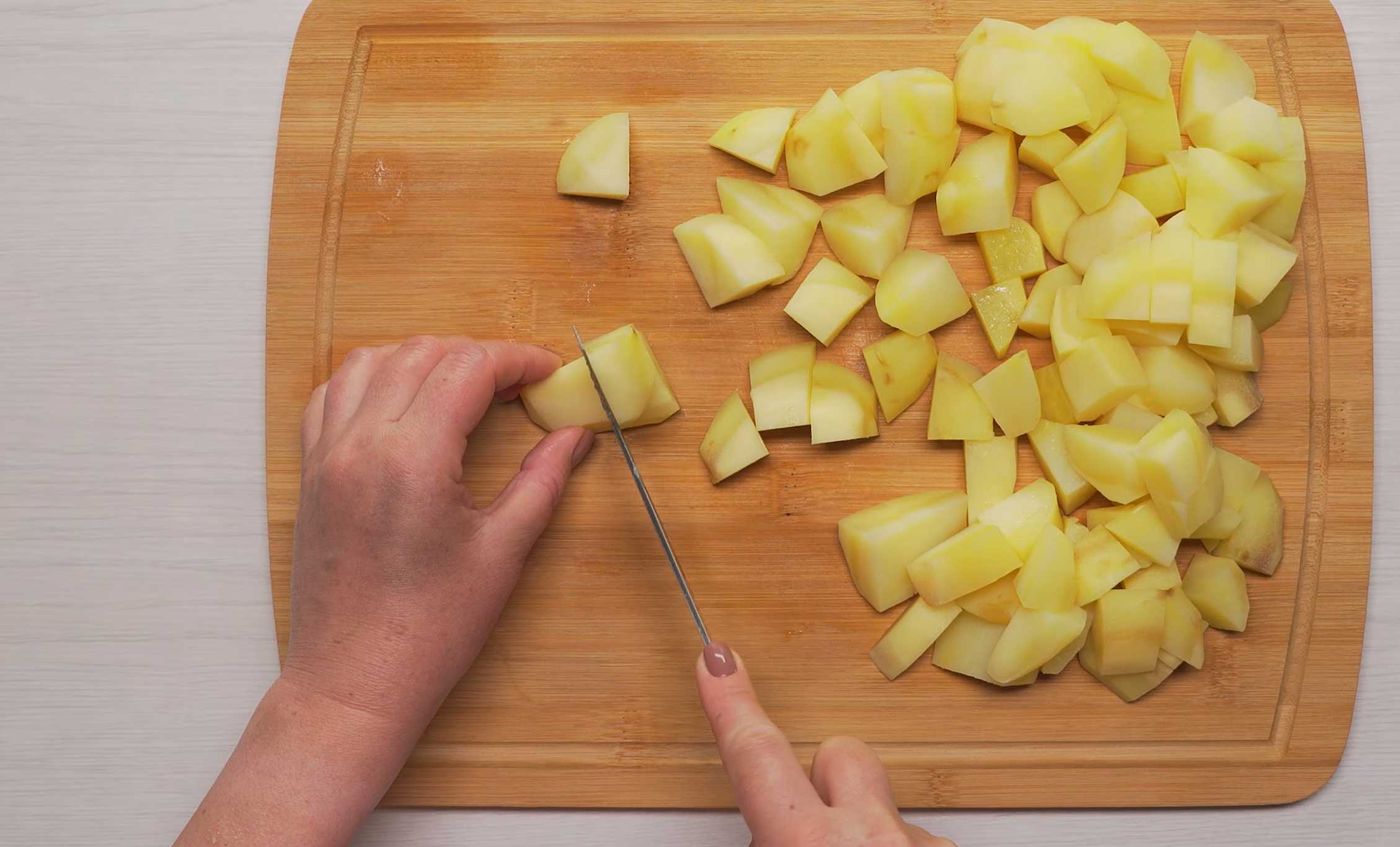 Нарежьте картофель на крупные кубики. Золотистая жареная картошка на сковороде-Шаг 3